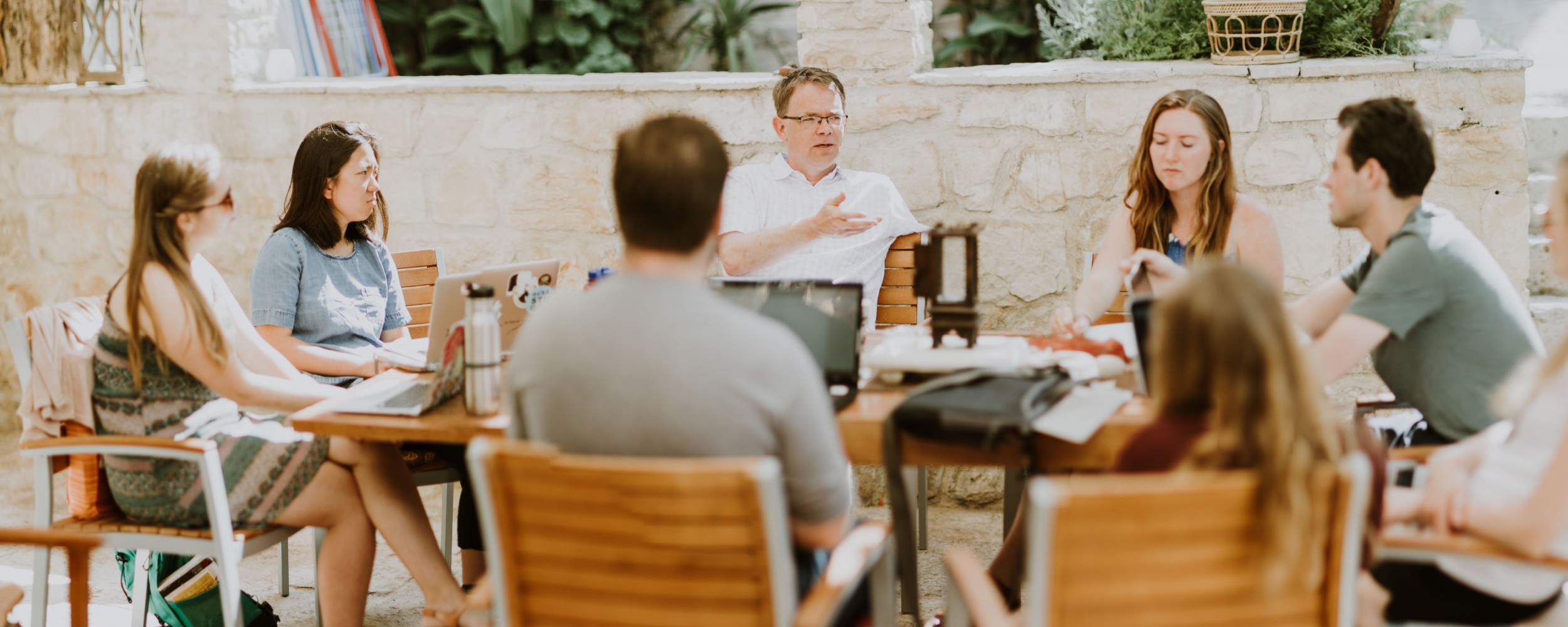 Students and professor gathered around outdoor table discussing work