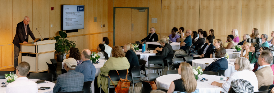 Room of people at the Hope and Health Conference listening to a speaker present