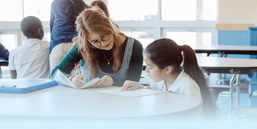 a graduate of Gordon College’s Master’s in education program working at an elementary school with a student.